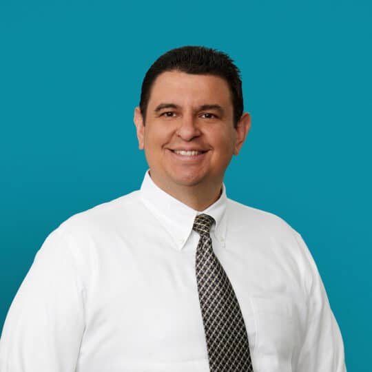 Professional headshot of Carlos Ventura, MD wearing white shirt and patterned tie