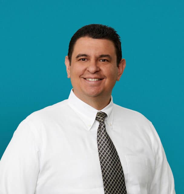 Professional headshot of Carlos Ventura, MD wearing white shirt and patterned tie