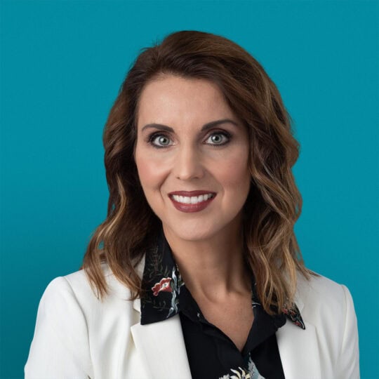 Professional headshot of Carmen C. Gruia, APRN-CNP in white blazer with floral top