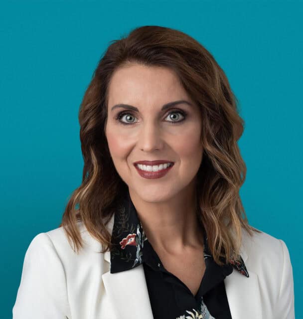 Professional headshot of Carmen C. Gruia, APRN-CNP in white blazer with floral top