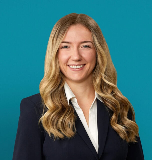 Professional headshot of Carolyn Goyne, PA-C in dark business suit against teal background