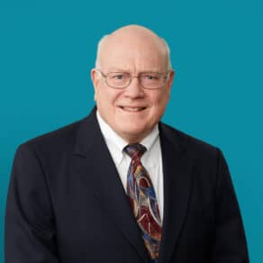 Professional headshot of Dr. Charles D. Horsley in dark suit against teal background