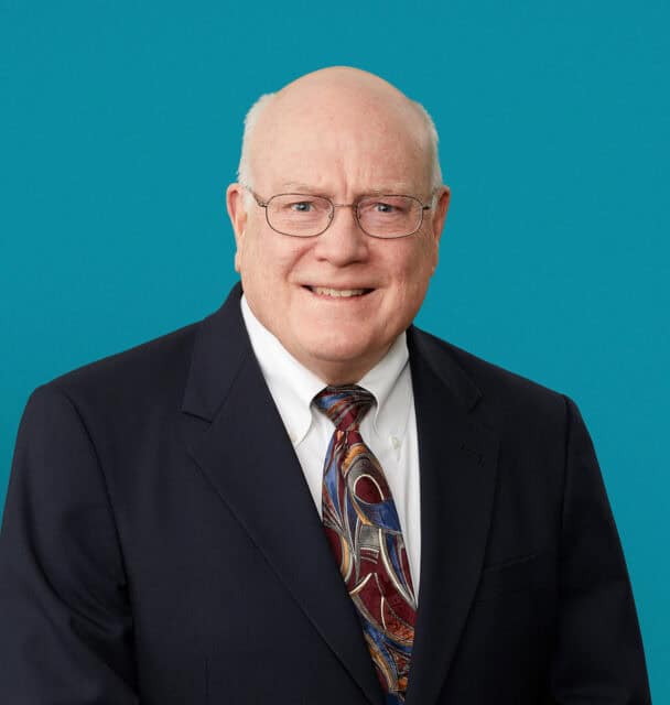 Professional headshot of Dr. Charles D. Horsley in dark suit against teal background