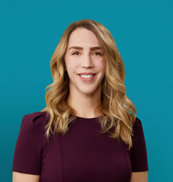 Professional headshot of Chelsea Zastrow, APRN-CNP, smiling in burgundy top against teal background