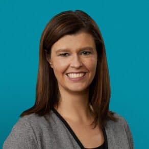 Professional headshot of Dr. Cherish J. Prutzman smiling in gray blazer against teal background