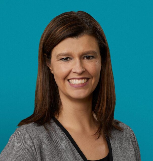 Professional headshot of Dr. Cherish J. Prutzman smiling in gray blazer against teal background