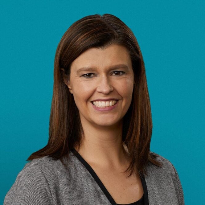 Professional headshot of Dr. Cherish J. Prutzman smiling in gray blazer against teal background