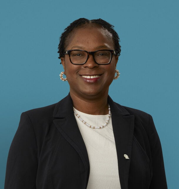 Professional headshot of Dr. Chika A. Ezigbo in black blazer against blue background