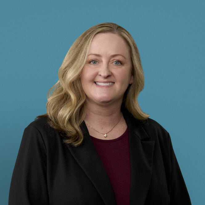 Professional headshot of Christie Astor, APRN-CNP, smiling in dark blazer against blue background
