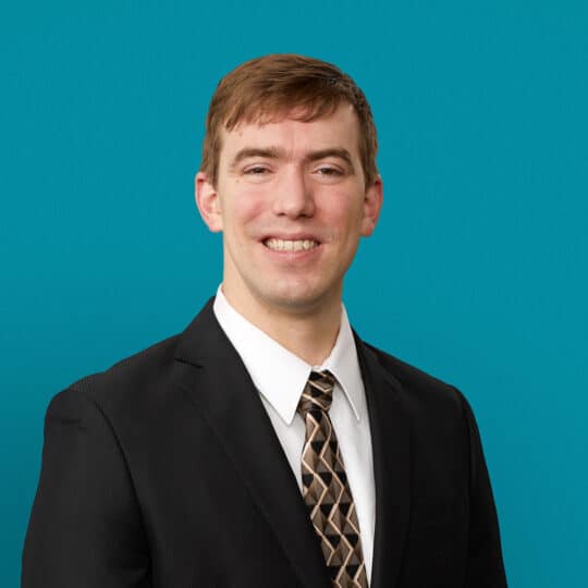 Professional headshot of Christopher M. Lawrence, APRN-CNP in dark suit against teal background