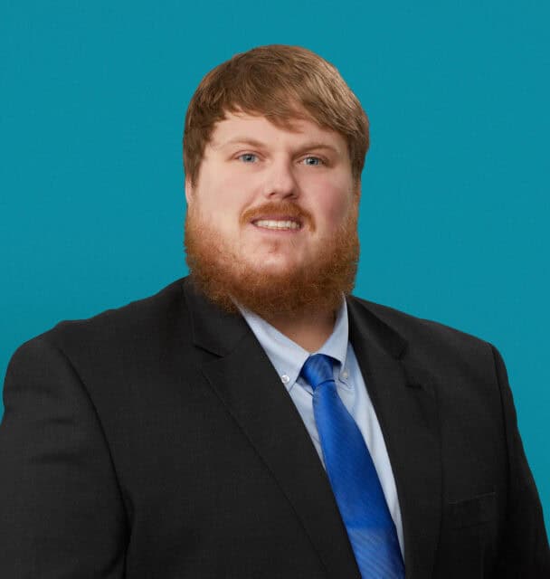 Professional headshot of Cody Cappel, APRN-CNP in dark suit with blue tie