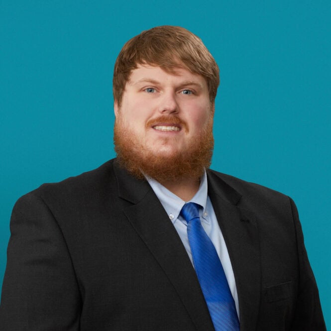 Professional headshot of Cody Cappel, APRN-CNP in dark suit with blue tie