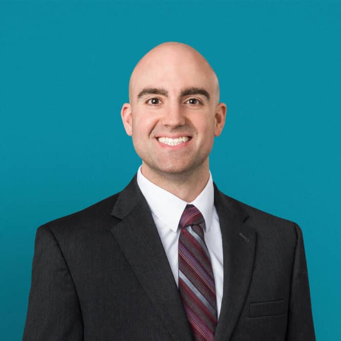 Professional headshot of Daniel Dekoski, DO in dark suit against teal background