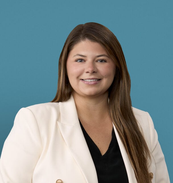 Professional headshot of Danielle Thomas, APRN-CNP in white blazer against blue background