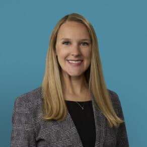 Professional headshot of Dr. Deanne R. Jacobs smiling in business attire against blue background.