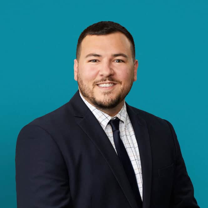 Professional headshot of Drew Guisinger, APRN-CNP in dark suit against teal background