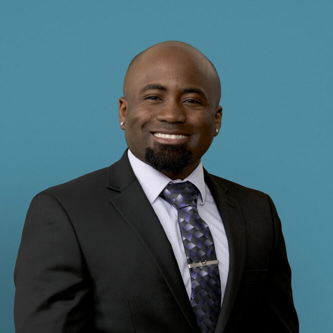 Professional headshot of Dylan Crowell, MD in dark suit with patterned tie, smiling