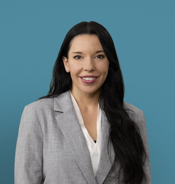 Professional headshot of Elise Stamper, APRN-CNP in gray blazer against blue background
