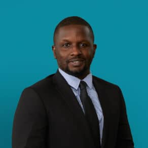 Professional headshot of Emmanuel Aguh, MD in dark suit against teal background