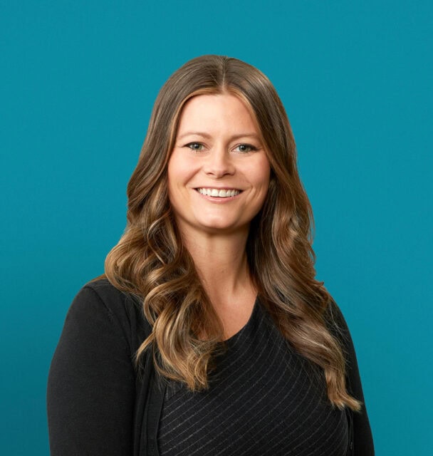 Professional headshot of Erin M. O'Neill, DO smiling in dark blazer against teal background