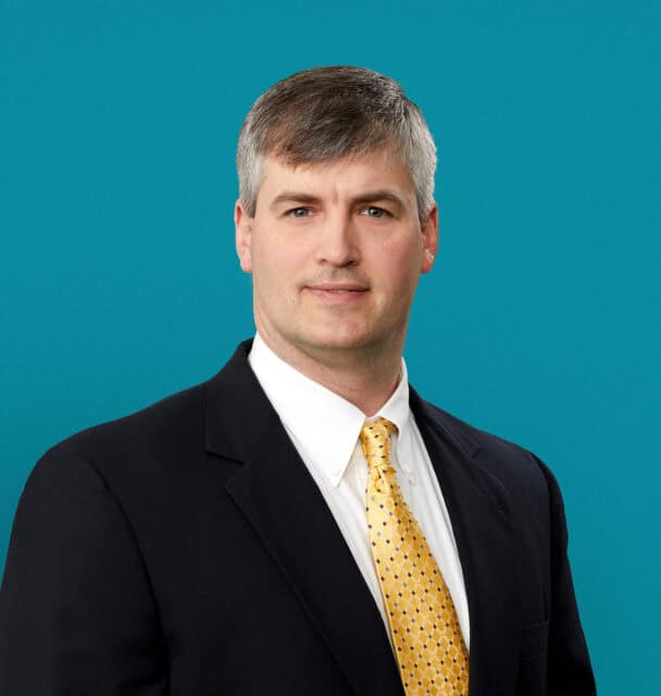Professional headshot of Hampton McClendon, MD in dark suit with yellow patterned tie