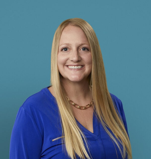 Professional headshot of Jaimie Kern, APRN-CNP in blue scrubs smiling at camera