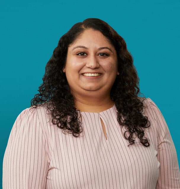 Professional headshot of Dr. Jalpa Soni smiling in pink striped blouse against teal background