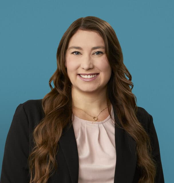 Professional headshot of Jamie J. Drake, APRN-CNP, smiling in business attire against blue background.