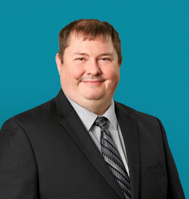 Professional headshot of Jason E. Morgan, APRN-CNP in dark suit against teal background
