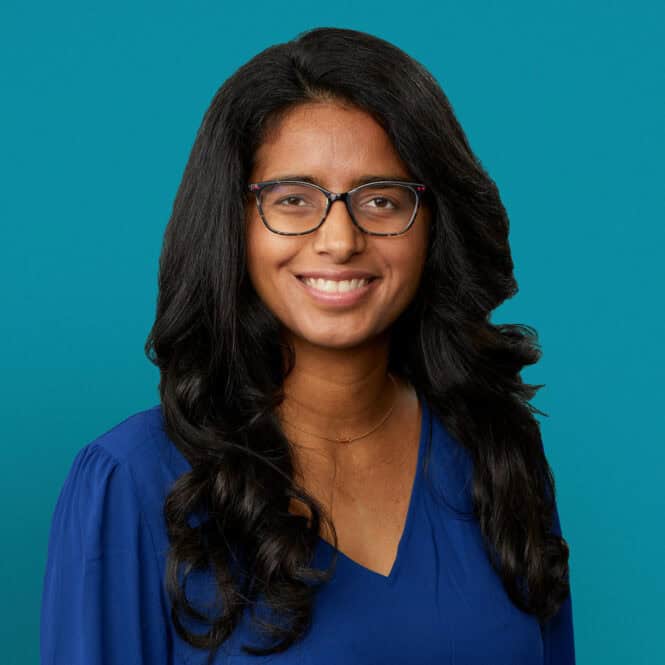 Professional headshot of Dr. Jaspreet Sandhu in blue top against teal background