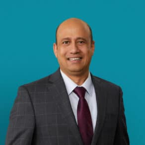 Professional headshot of Dr. Jayanta T. Mukherjee in gray suit with burgundy tie