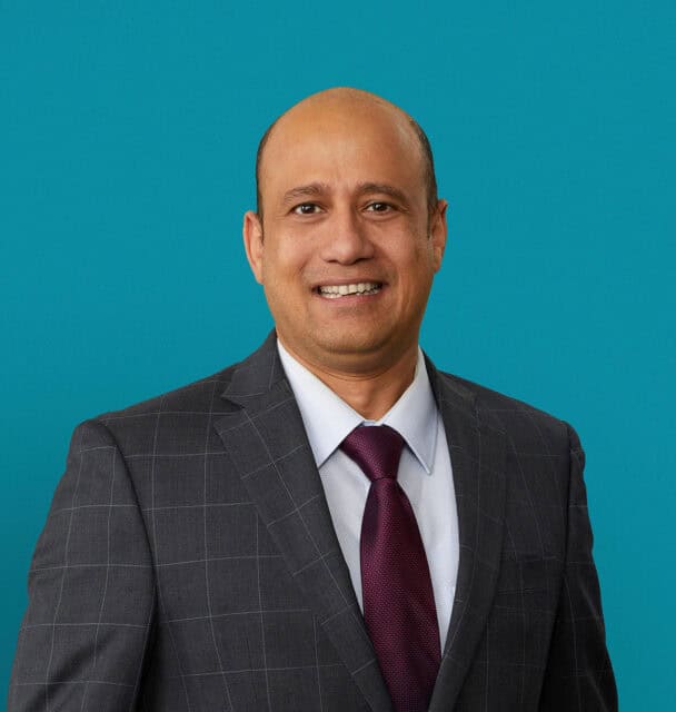 Professional headshot of Dr. Jayanta T. Mukherjee in gray suit with burgundy tie