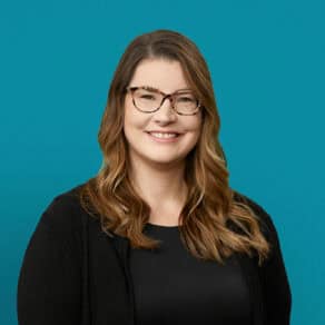 Professional headshot of Dr. Jerika Ortlieb smiling in black blazer against teal background