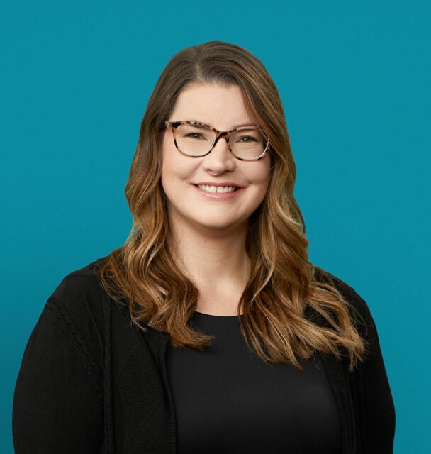 Professional headshot of Dr. Jerika Ortlieb smiling in black blazer against teal background