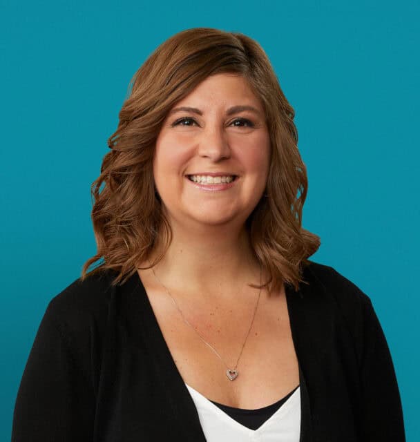 Professional headshot of Jessica Cooper, APRN-CNP, smiling in black cardigan against teal background