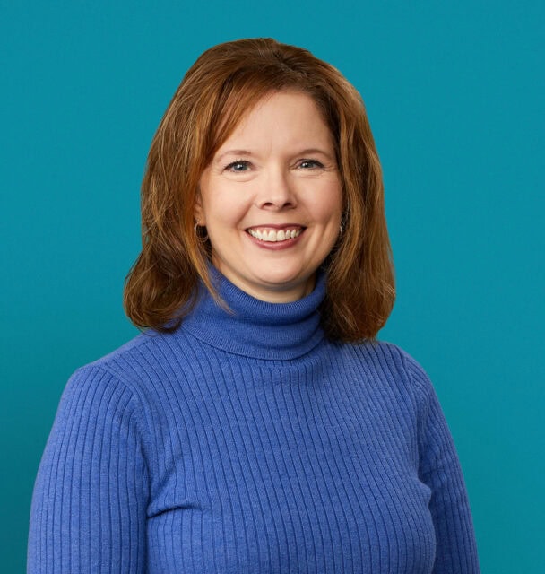 Professional headshot of Jessica Roten, PharmD wearing blue turtleneck sweater against teal background