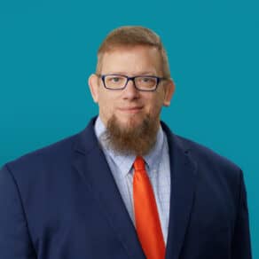 Professional headshot of John Allen, PA-C in navy suit with orange tie
