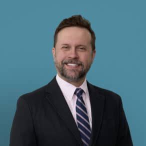 Professional headshot of Dr. Jonathan Toot smiling in dark suit and striped tie