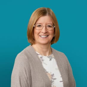 Professional headshot of Dr. Karen E. Starrett smiling against turquoise background