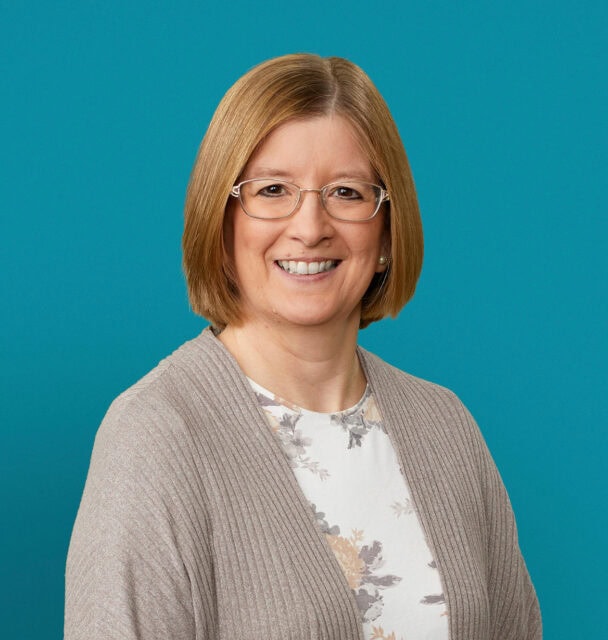 Professional headshot of Dr. Karen E. Starrett smiling against turquoise background