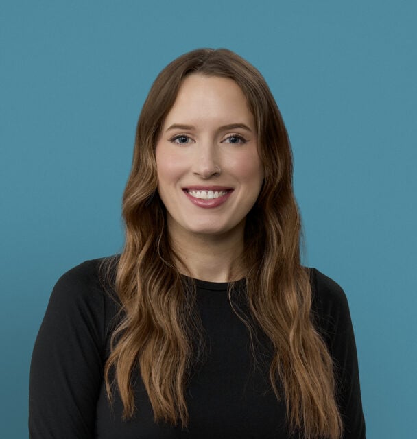 Professional headshot of Katelyn Wilson, APRN-CNP, smiling in black top against blue background