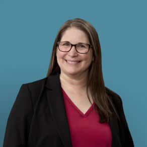 Professional headshot of Kathleen Fuchs wearing glasses, black blazer and red top