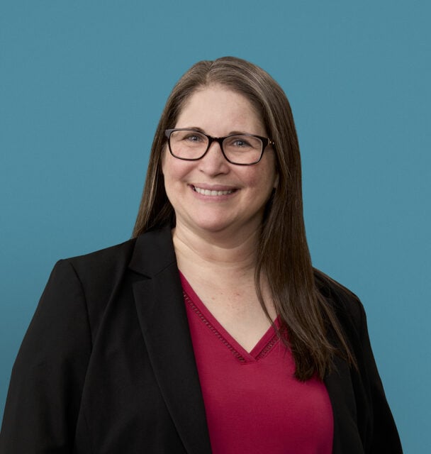 Professional headshot of Kathleen Fuchs wearing glasses, black blazer and red top