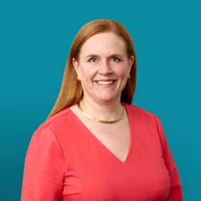 Professional headshot of Dr. Kathleen J. Oxner in coral top against teal background