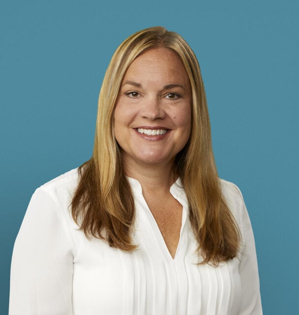 Professional headshot of Katy Boyd, RN, smiling in white blouse against blue background
