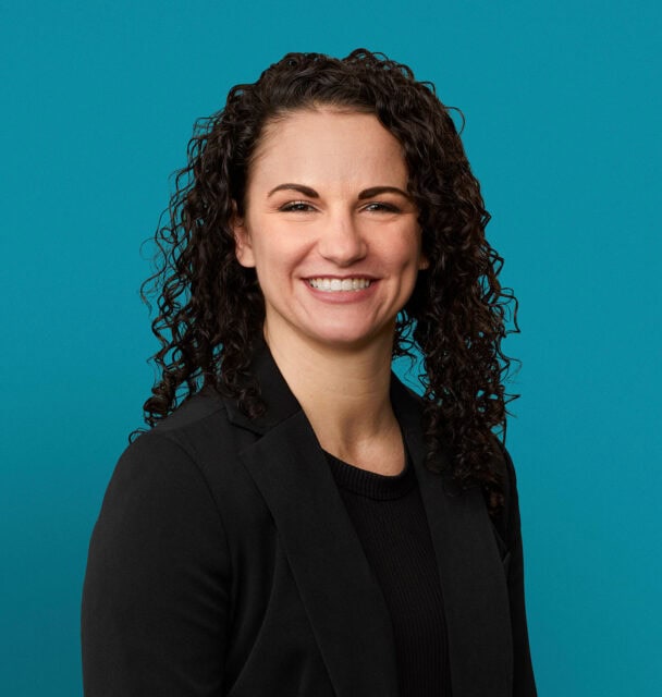 Professional headshot of Kayli D. Johnson, APRN-CNP, smiling in dark blazer against teal background.