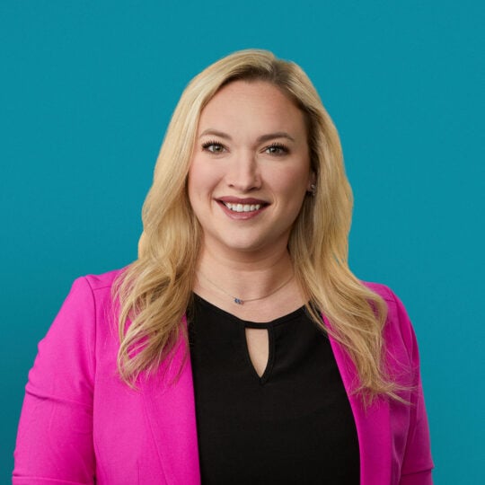Professional headshot of Kelsey Matthews, PA-C in bright pink blazer smiling at camera