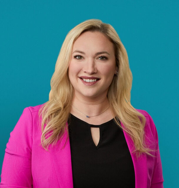 Professional headshot of Kelsey Matthews, PA-C in bright pink blazer smiling at camera