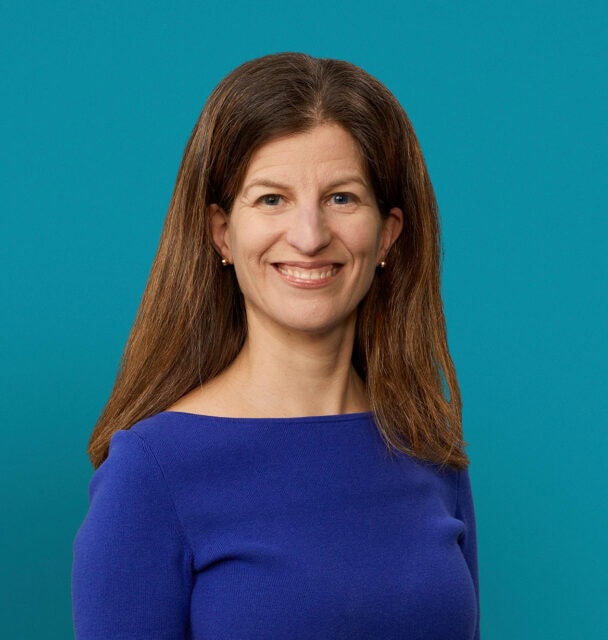 Professional headshot of Dr. Keren Ray in blue top against teal background