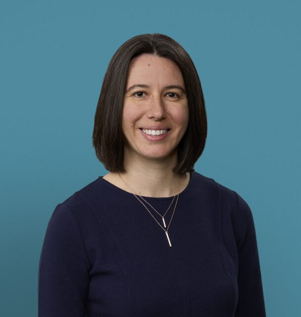 Professional headshot of Dr. Kerianne Springer smiling in navy top against blue background